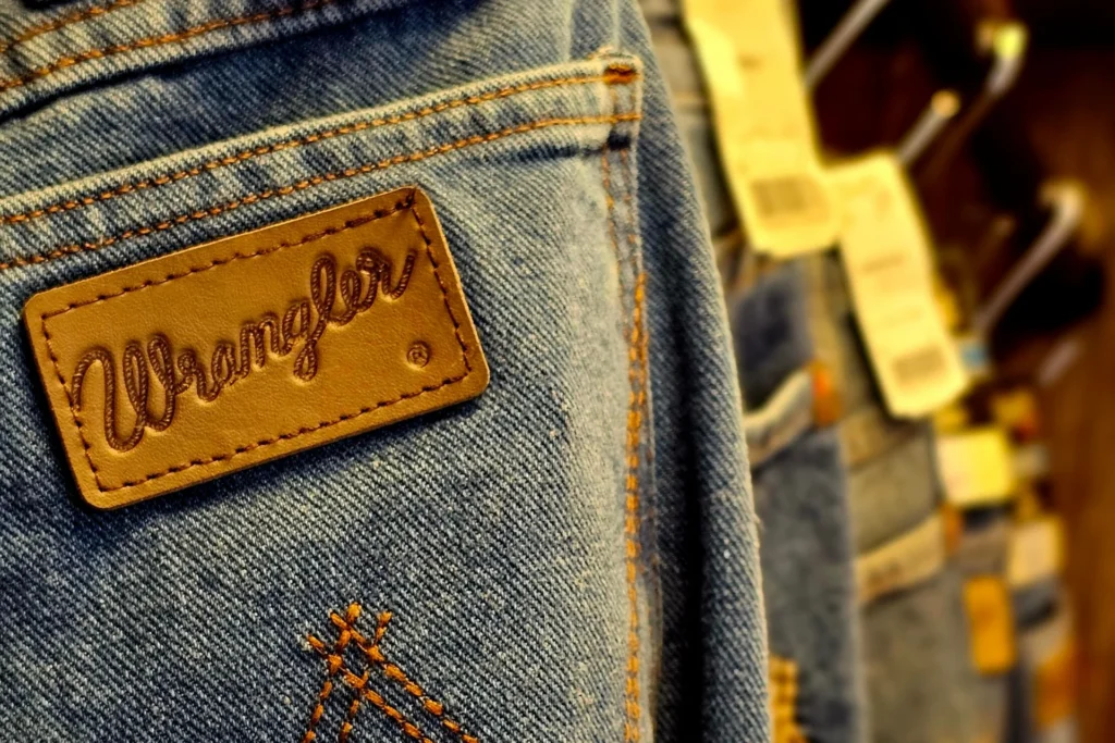 Szczegółowe zbliżenie dżinsów Wrangler, starannie wiszących w rzędzie w sklepie odzieżowym.